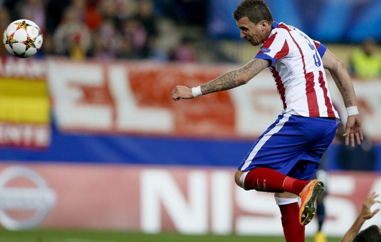 El delantero croata del Atlético de Madrid, Mario Mandzukic (i), cabecea para conseguir el tercer gol del equipo, durante el encuentro de la fase de grupos, grupo A, de la Liga de Campeones que Atlético y Olympiacos disputan esta noche en el estadio Vicen