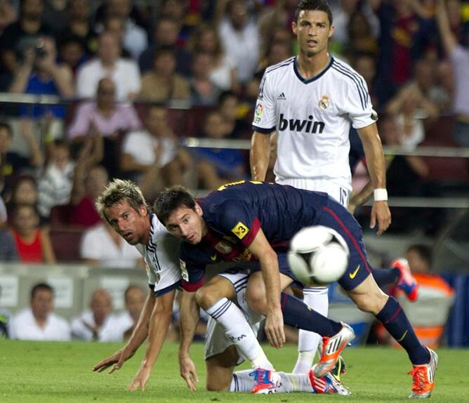 El defensa portugués del Real Madrid Coentrao lucha el balón con el argentino Leo Messi, del FC Barcelona, junto a Cristiano Ronaldo, durante el partido de ida de la Supercopa de España