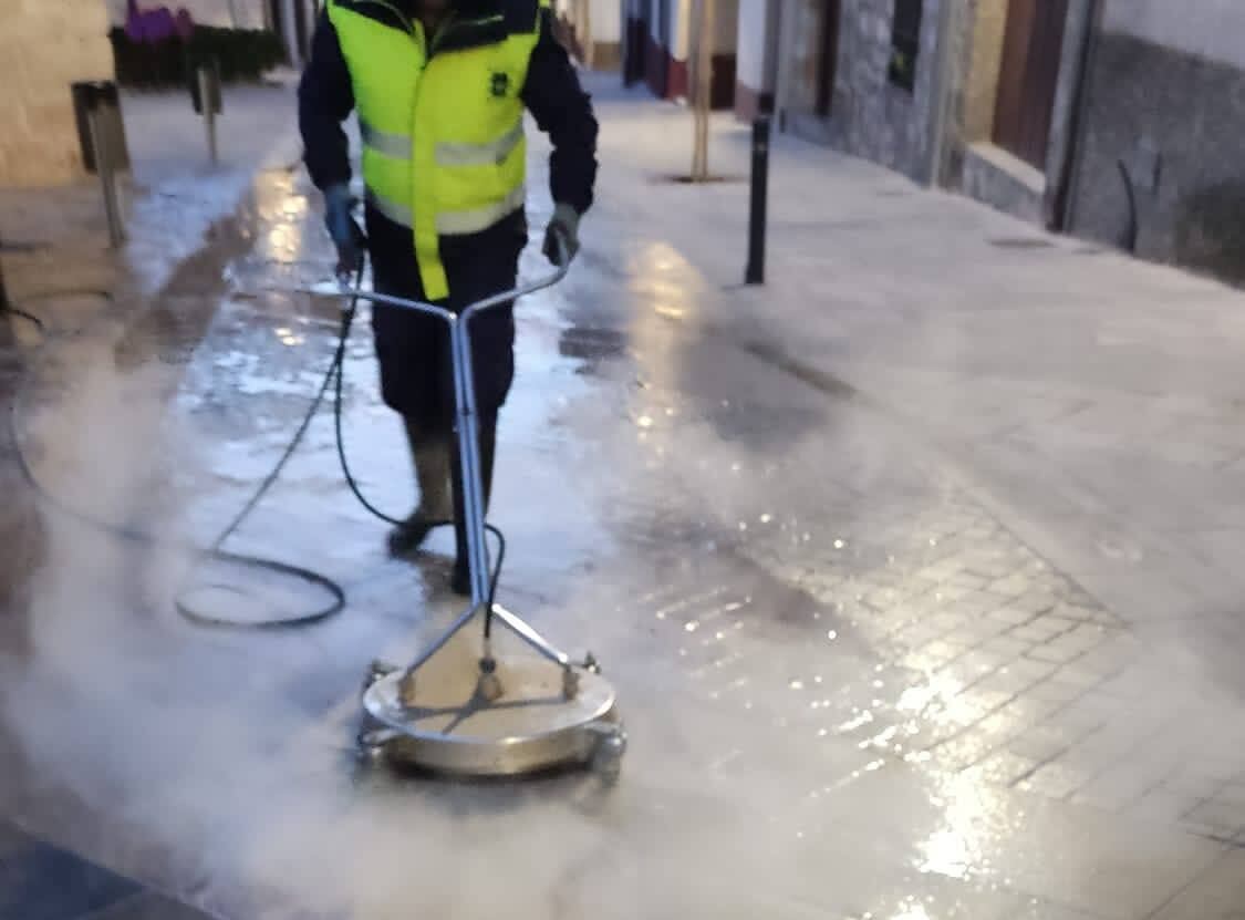 Un empleado municipal del Servicio de Limpieza elimina la cera derramada en la calle durante una procesión de Semana Santa