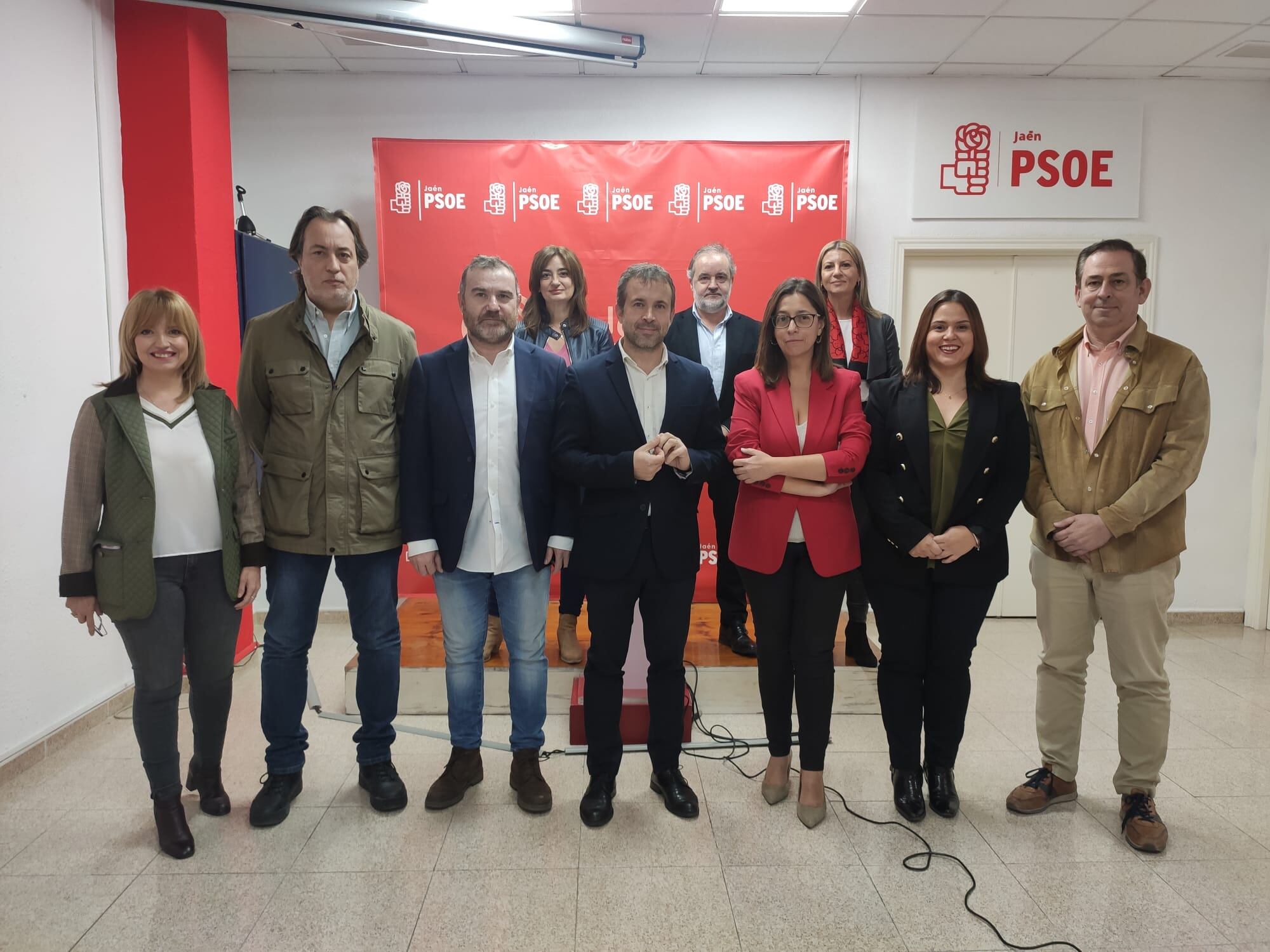 Los concejales y concejalas del PSOE de Jaén capital, escoltados en el centro por Julio Millán, en la sede del partido