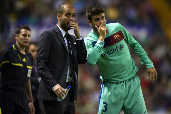 Gerard Piqué y Pep Guardiola hablan en el terreno de juego.