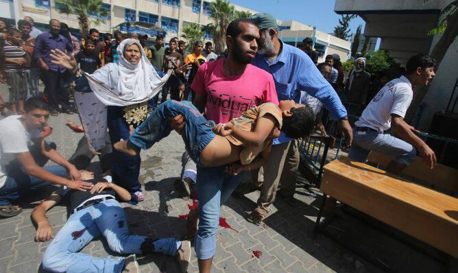 Un palestino acarreando el cuerpo de un niño tras el ataque Israelí en la escuela de la ONU en Rafah (Gaza)