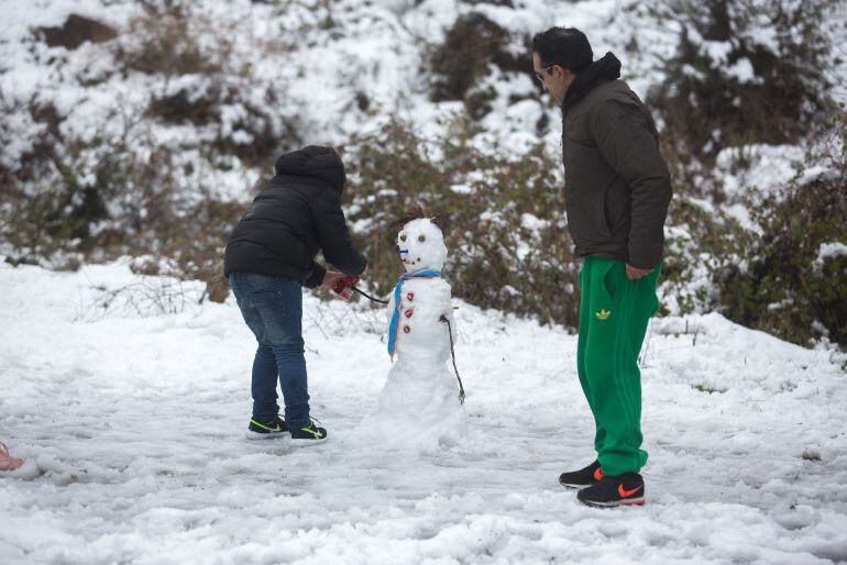 Un padre y su hijo realizan un muñeco de nieve en la carretera A-397 a la altura del desvío de Juzcar en Marbella (Málaga), donde esta mañana se ha tenido que cortar la carretera por la acumulación de nieve