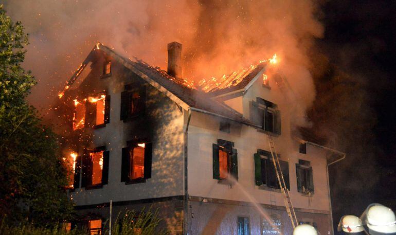 Varios bomberos trabajan en la extinción de un incendio declarado en un edificio vacío que debía convertirse en un hogar para refugiados en la localidad de Weissach im Tal, suroeste de Alemania, en la madrugada de 24 de agosto de 2015.