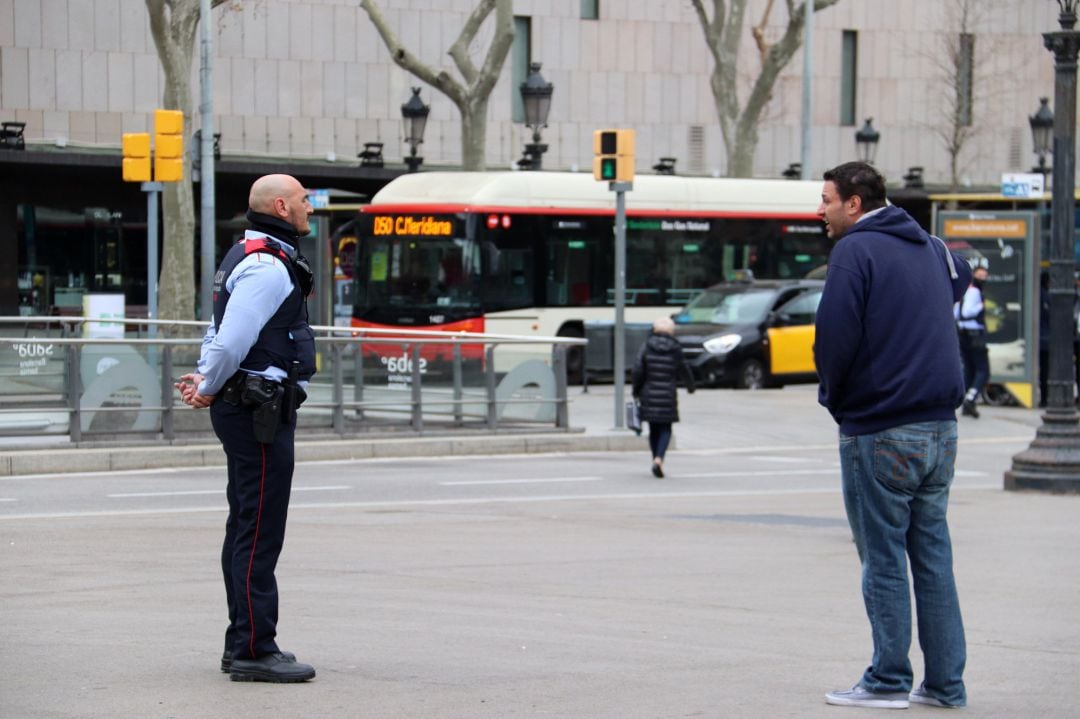 Un agent dels Mossos pregunta el destí i motiu del viatge a un vianant a la plaça Catalunya de Barcelona