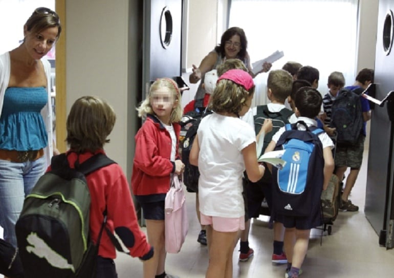 Alumnos y profesoras a la entrada de las aulas de un colegio