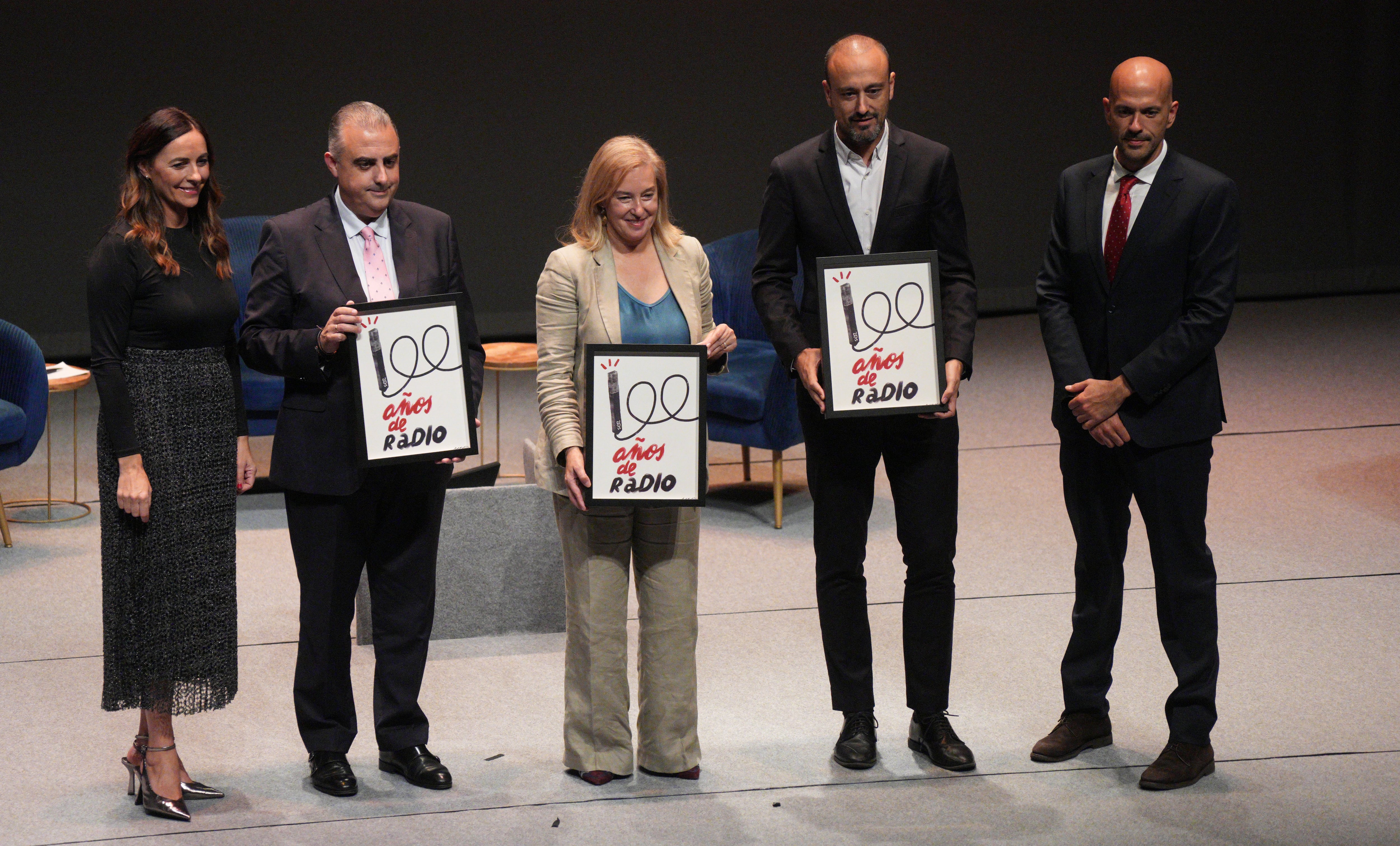 El consejero de Fomento, la presidenta del Parlamento de Cantabria y el alcalde de Torrelavega recibieron una litografía del centenario de la radio.