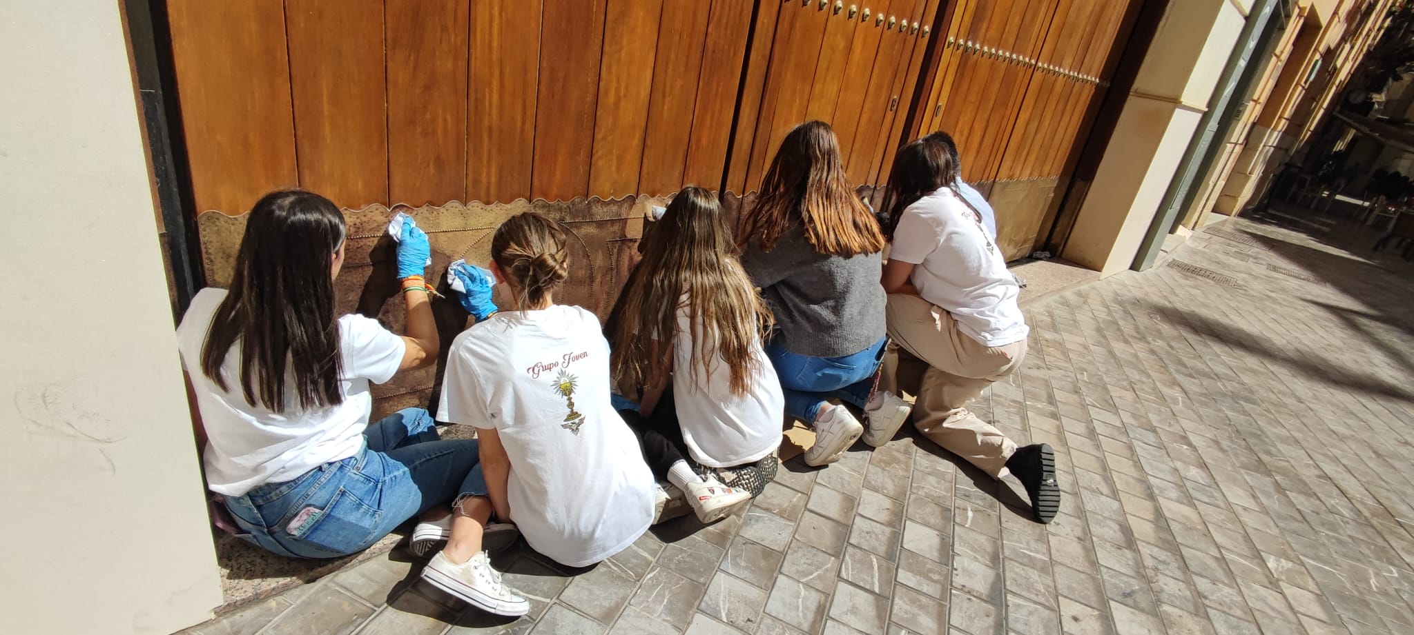 Grupo Joven la cofradía de la Cena. Sacando lustre a la puerta de la casa hermandad de calle Compañía