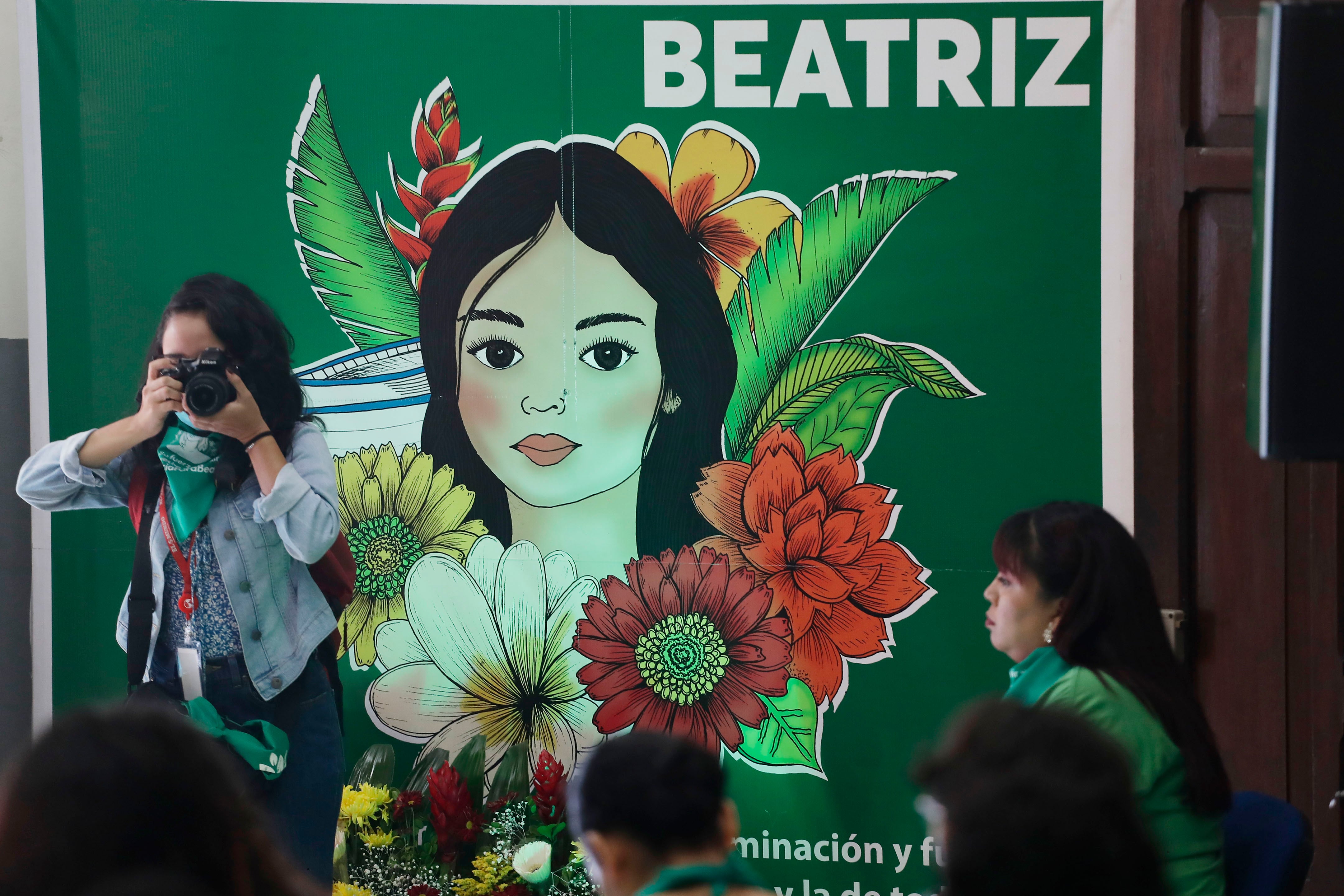 AME4762. SAN SALVADOR (EL SALVADOR), 22/03/2023.- Vista hoy de un cartel con el rostro de la fallecida Beatriz, una joven salvadoreña a quien en 2013 se le impidió interrumpir su embarazo, durante la transmisión de una audiencia de la CorteIDH sobre su caso, en San Salvador (El Salvador). Organizaciones feministas y de derechos humanos de El Salvador esperan que el fallo que emita la Corte Interamericana de Derechos Humanos (CorteIDH), que este miércoles conoce el caso sobre aborto de &#039;Beatriz&#039;, recomiende que &quot;se despenalice el aborto&quot; en este país centroamericano &quot;al menos por causales&quot;. EFE/Rodrigo Sura
