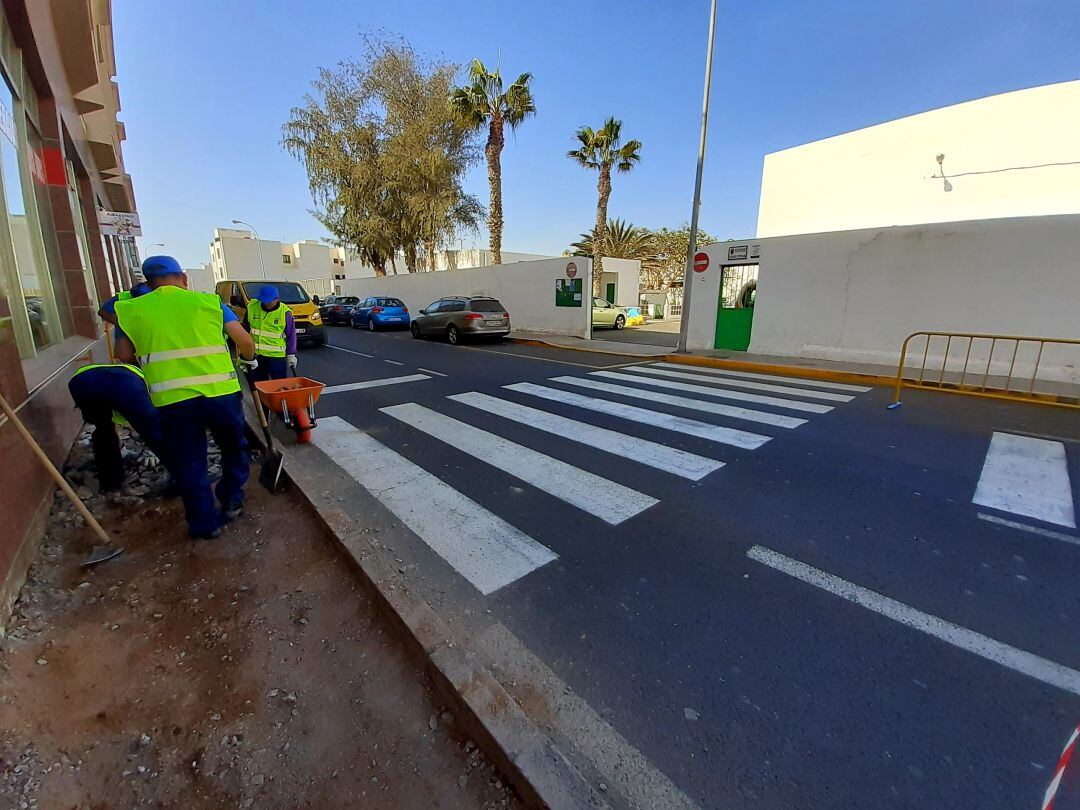 Operarios trabajando en las aceras situadas frente a uno de los colegios.