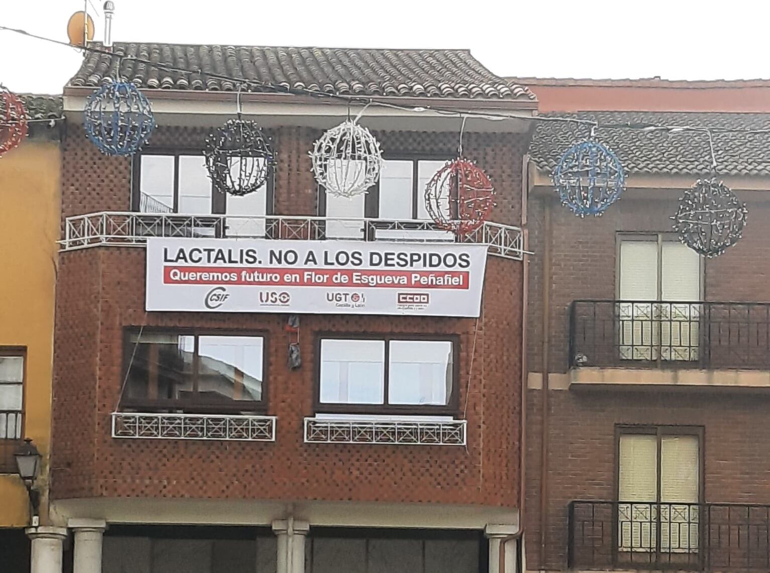 La pancarta que puede observarse en la Plaza de España de Peñafiel sobre el 'No a los despidos' en Flor de Esgueva