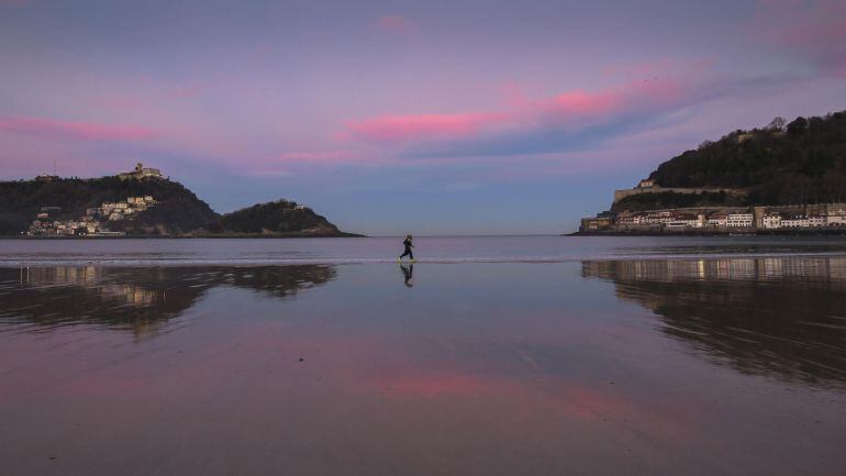 Dos personas corren al amanecer por la orilla de la playa de La Concha de San Sebastián.