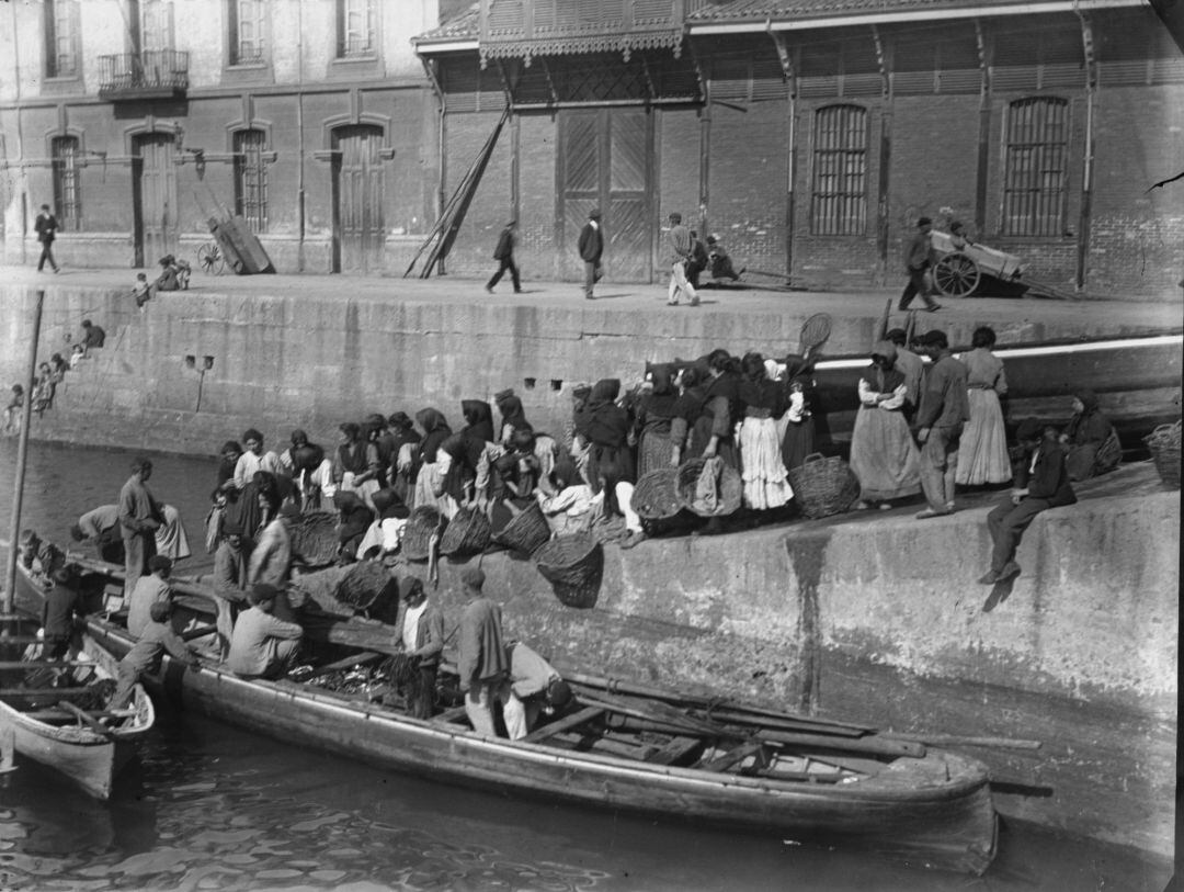 Mujeres recogiendo el pescado a la llegada de las lanchas en el muelle de Gijón. Imagen expuesta en el pabellón del Ayuntamiento de Gijón de la 64 Feria Internacional de Muestras de Asturias